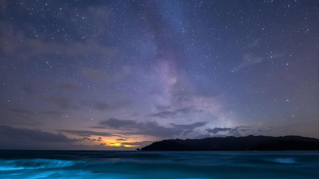 石垣島の夜空に輝く天の川と、青く光る海面イメージ