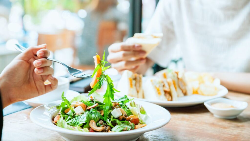 石垣島のカフェでランチを楽しむ2人。手前はサラダ、奥はサンドイッチを食べている。